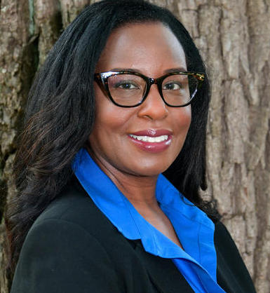 headshot of woman in black blazer and glasses 