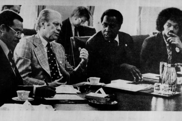 Old black and white photo of Black men discussing with white man