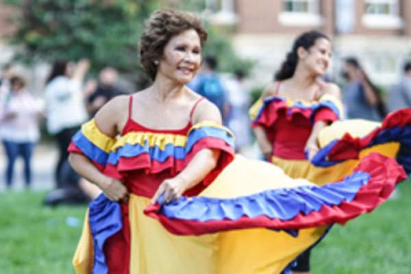 Women dancing in a red, blue and yellow dress. 
