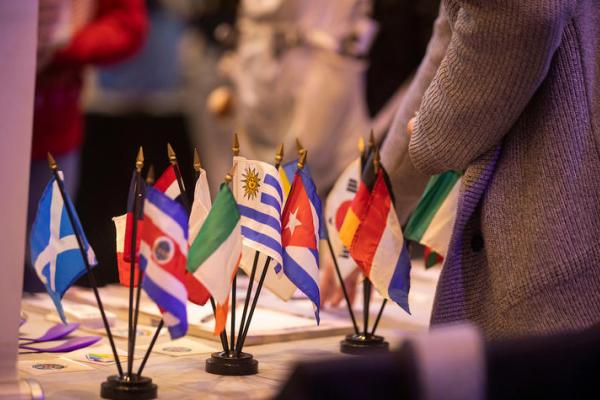 Multiple countries' flags sitting on a table. 