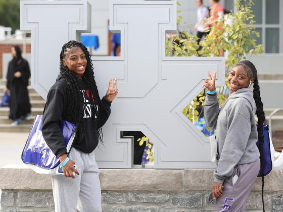 two students posing in front of UK logo at the Alumni Commons block party