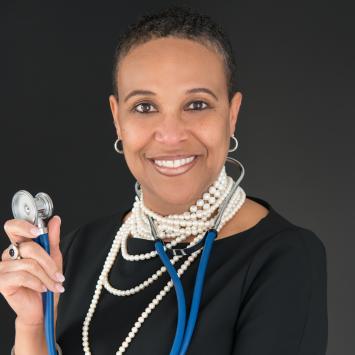 woman smiling for headshot in black shirt while holding a stethoscope 